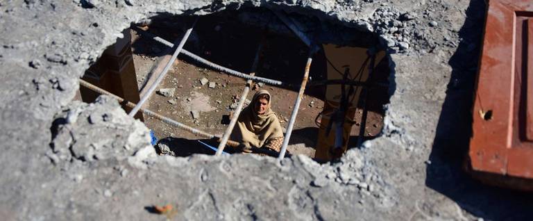 A Pakistani Kashmiri woman is seen through a hole on the roof of a house caused by cross-border shelling at Dhanna village, on the Line of Control that divides Kashmir between Pakistan and India, on March 5, 2019.
