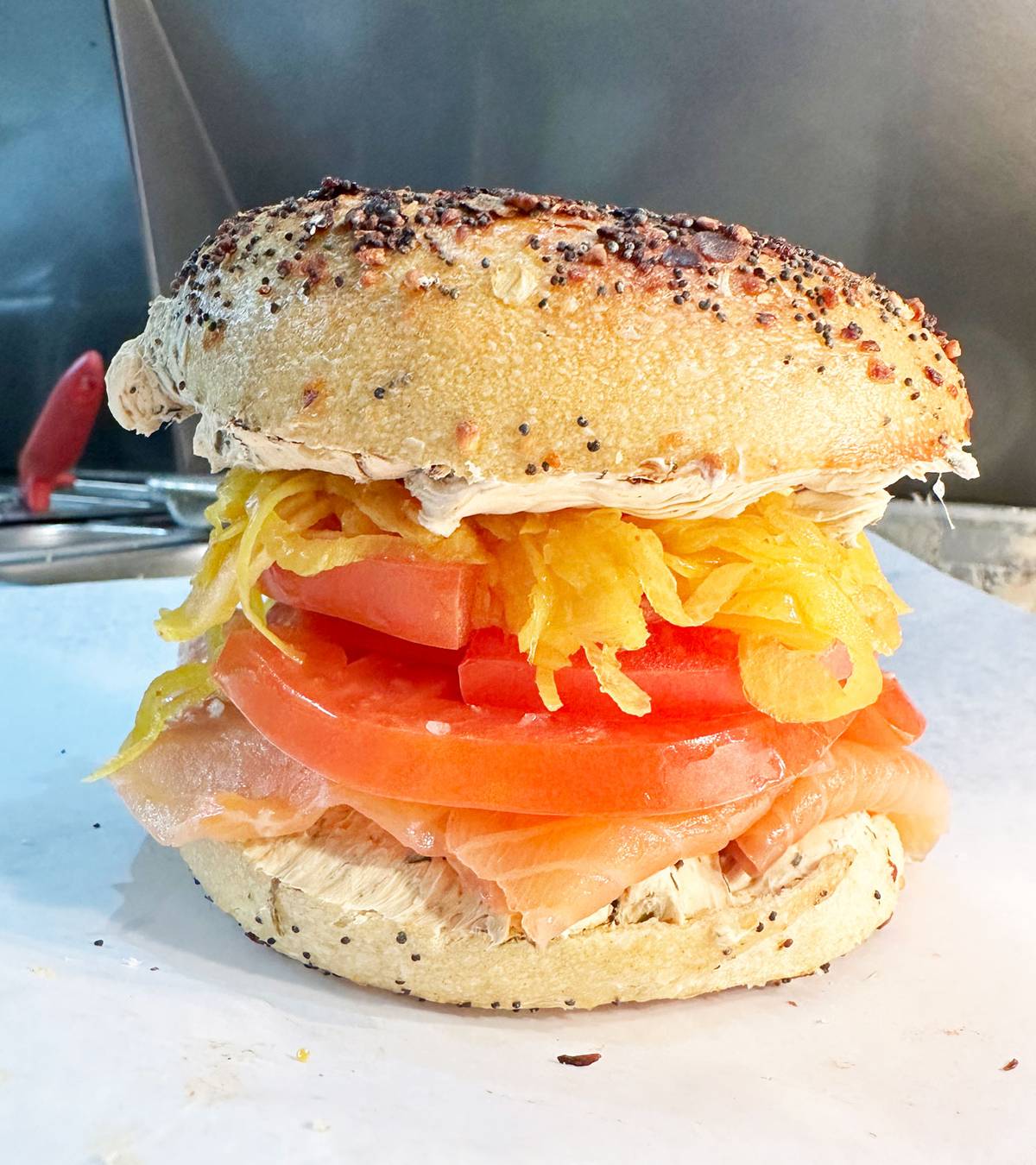 House smoked salmon, layered with charred scallion cream cheese, amba-pickled shallots, and heirloom tomato, on a Chicago-style everything bagel from Edith's in Brooklyn