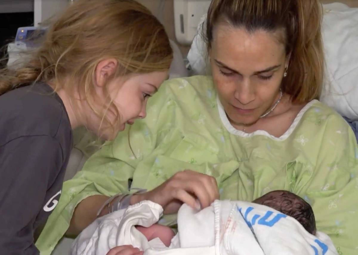 Avital in the hospital with her new baby, as one of her older daughters looks on
