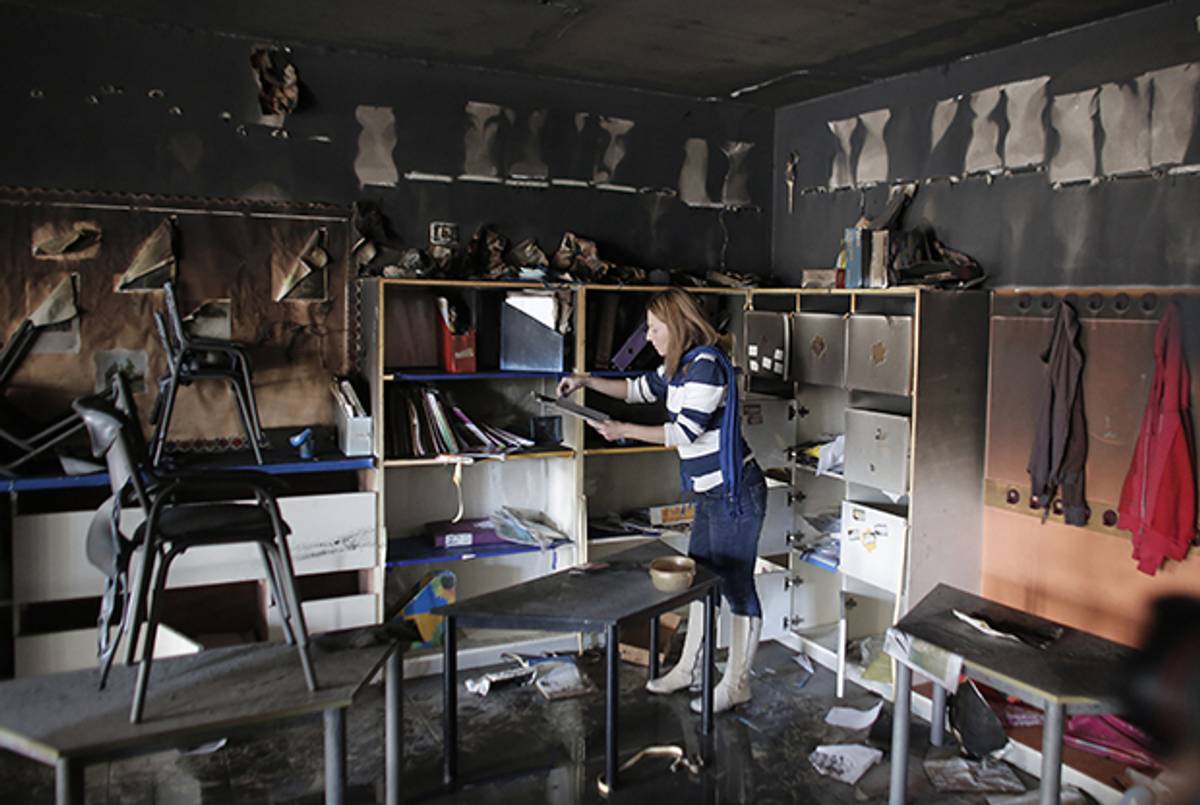 A woman inspects the damage on the aftermath of an arson attack that targeted first-grade classrooms at a Jewish-Arab school near the Arab neighborhood of Beit Safafa, in southern Jerusalem, on November 30, 2014. (AHMAD GHARABLI/AFP/Getty Images)