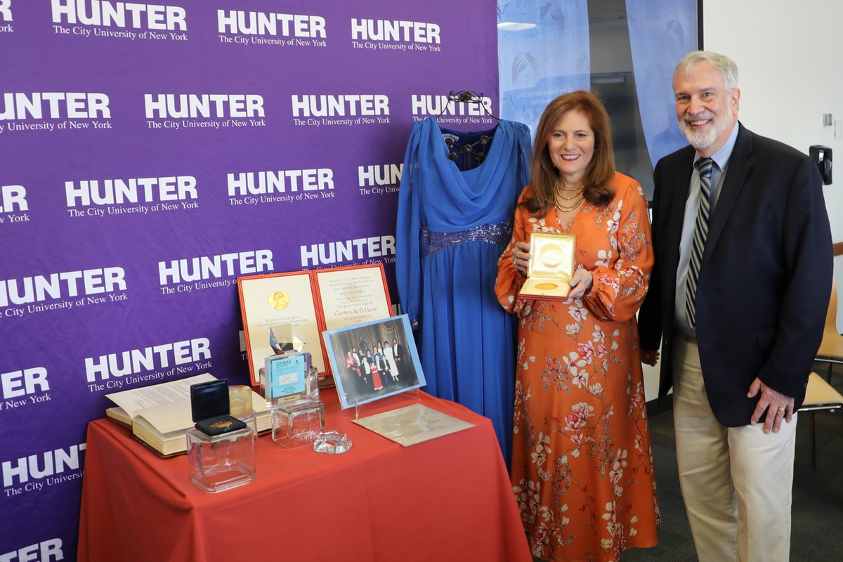 Hunter College President Jennifer J. Raab, pictured with Jonathan Elion, holds Gertrude Elion’s Nobel Prize award. At her left is the dress Gertrude wore to receive her prize in 1988.