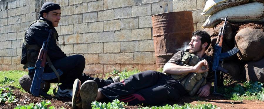 Syrian rebel fighters rest in a field in the countryside on the outskirts of the central Syrian city of Homs, March 1, 2016. 