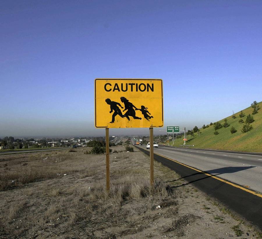A sign is posted on a freeway warning drivers of people crossing in San Ysidro, California