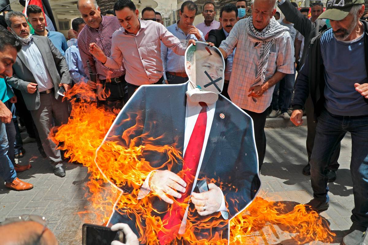 Palestinian men burn a cardboard cutout of U.S. Secretary of State Mike Pompeo during a protest against his visit to Israel, on May 14, 2020, in Nablus