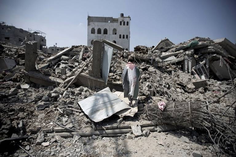 A Palestinian man, wrapped in his national flag, inspects the rubble of destroyed buildings and houses in the Shejaiya residential district of Gaza City, on July 28, 2014. (Getty Images)