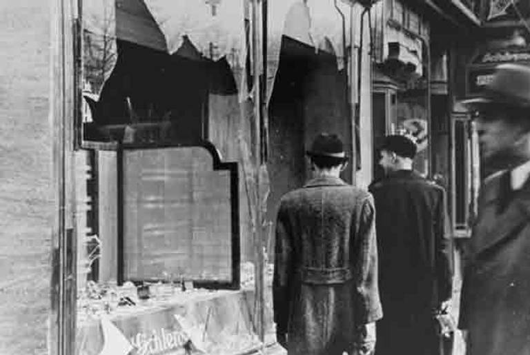 Germans pass by the broken shop window of a Jewish-owned business that was destroyed during Kristallnacht. (US Holocaust Memorial Museum, courtesy of National Archives and Records Administration, College Park, MD)