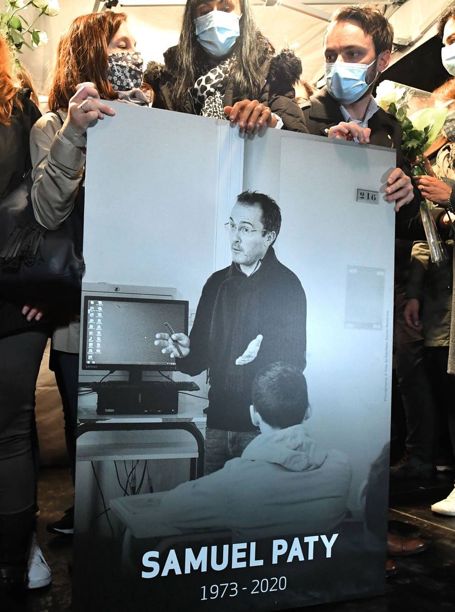 Relatives and colleagues hold a picture of Samuel Paty during the ‘Marche Blanche’ in Conflans-Sainte-Honorine, northwest of Paris, on Oct. 20, 2020, in solidarity after the teacher was beheaded for showing pupils cartoons of the Prophet Mohammed