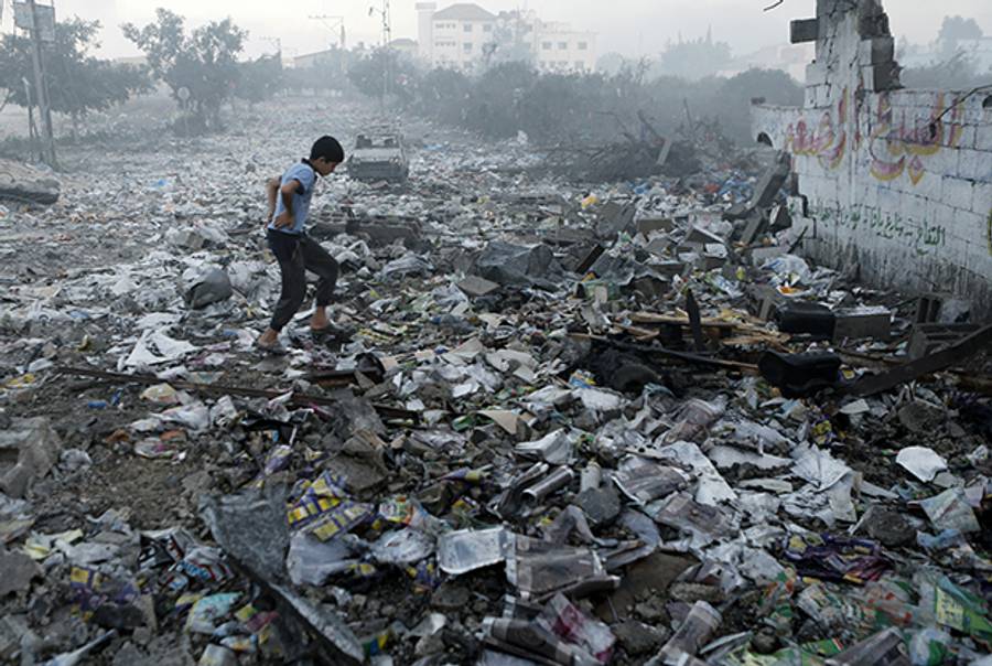A Palestinian youth walks on debris as he inspects damages following an Israeli air strike in Gaza City, on July 24, 2014. (MOHAMMED ABED/AFP/Getty Images)
