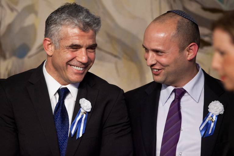 Israeli politician Yair Lapid, at left, leader of the Yesh Atid party, speaks to Naftali Bennett, right, then head of the Jewish Home party, during a reception on Feb. 5, 2013. The two are slated to rotate as prime minister in a new Israeli government.