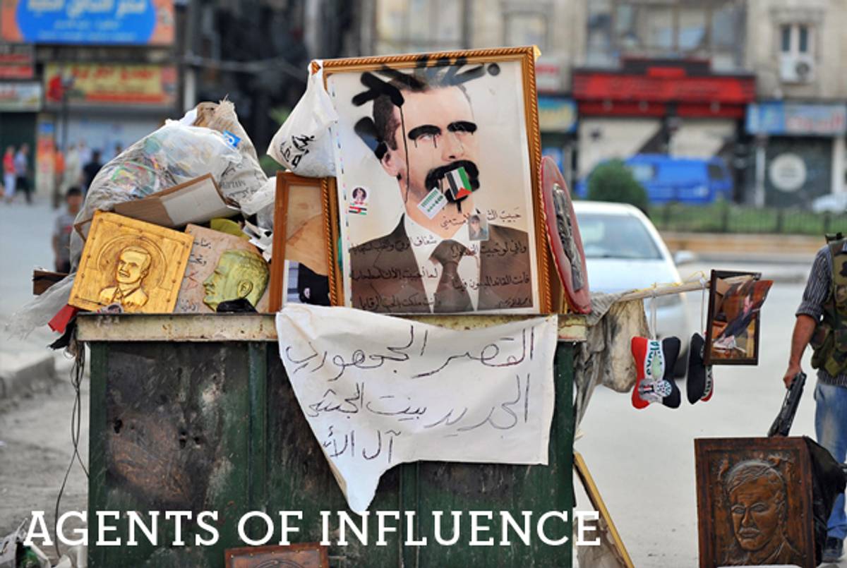 A Syrian rebel stands near a vandalized portrait of Syrian President Bashar al-Assad in the city of Selehattin, near Aleppo, on July 23, 2012. (Bulent Kilic/AFP/Getty Images)