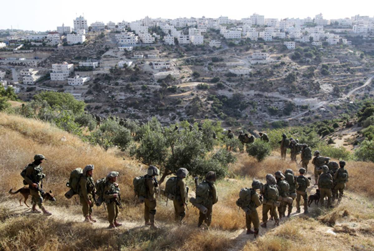 Israeli soldiers walk in a single file on a path during an operation in the West Bank town of Hebron on June 17, 2014 as Israeli forces broadened the search for three teenagers believed kidnapped by militants and imposed a tight closure of the town. (HAZEM BADER/AFP/Getty Images)