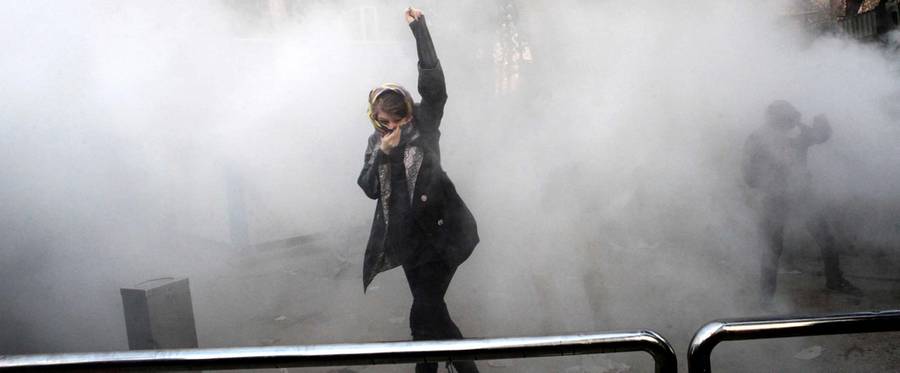 An Iranian woman raises her fist amid the smoke of tear gas at the University of Tehran during a protest driven by anger over economic problems, in the capital Tehran on December 30, 2017. Students protested in a third day of demonstrations sparked by anger over Iran's economic problems, videos on social media showed, but were outnumbered by counter-demonstrators.