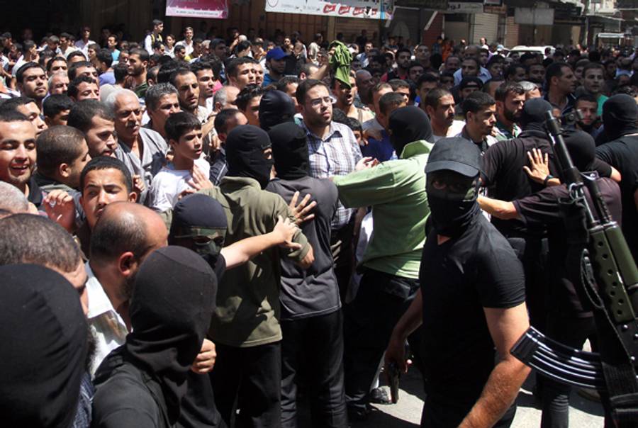 Armed Palestinian masked militants push back a crowd of worshippers outside a mosque in Gaza City after Friday prayers on August 22, 2014, before executing 18 men for allegedly helping Israel in its six-week assault on the Palestinian enclave. (STR/AFP/Getty Images)