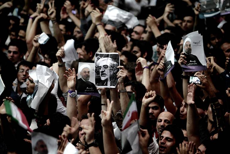 A supporter of Iranian former Vice-President Mohammad Reza Aref holds a portrait of opposition leader Mir Hossein Mousavi, who is under house arrest since February 2011, during a campaign rally for Aref in Tehran on June 10, 2013.(Behrouz Mehri/AFP/Getty Images)