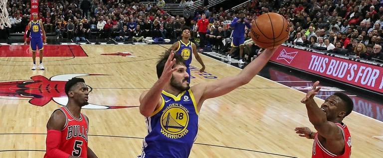 Omri Casspi #18 of the Golden State Warriors rebounds between Bobby Portis #5 (L) and David Nwaba #11 of the Chicago Bulls at the United Center on January 17, 2018 in Chicago, Illinois.