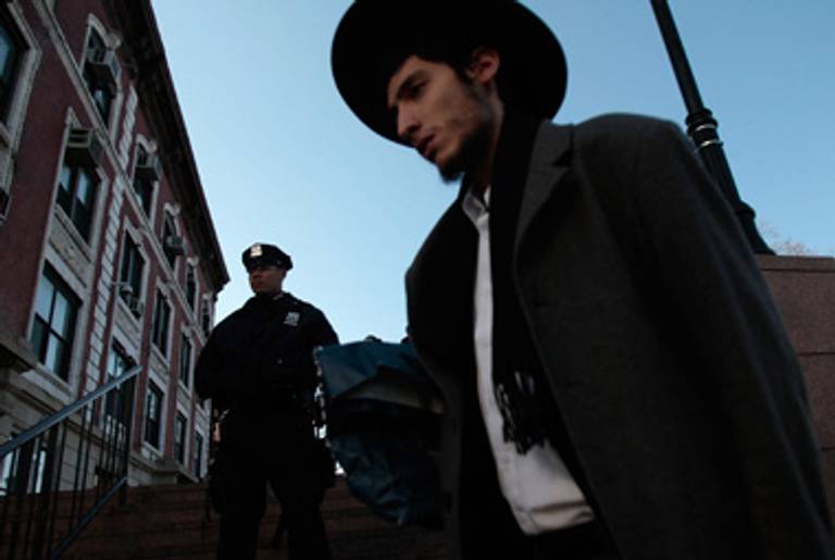 A Lubavitcher walks by a policeman, in Crown Heights, in 2008.(Chris Hondros/Getty Images.)