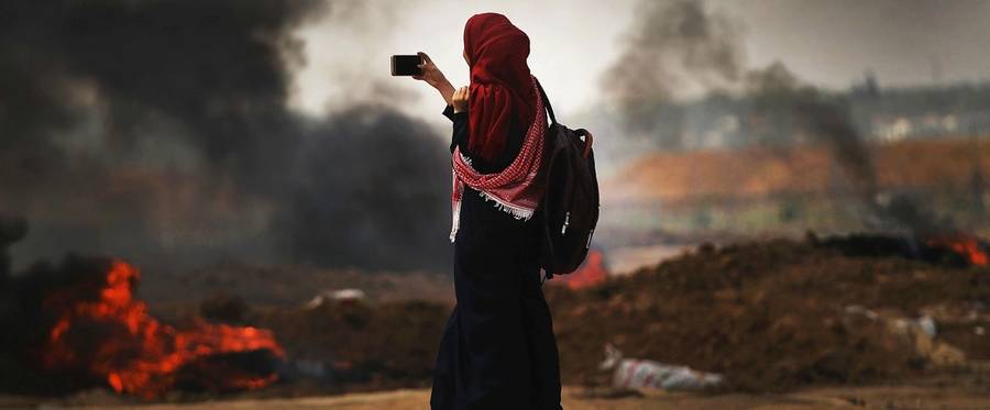 A Palestinian woman documents the situation at the border fence with Israel as mass demonstrations continue on May 14, 2018 in Gaza City, Gaza.