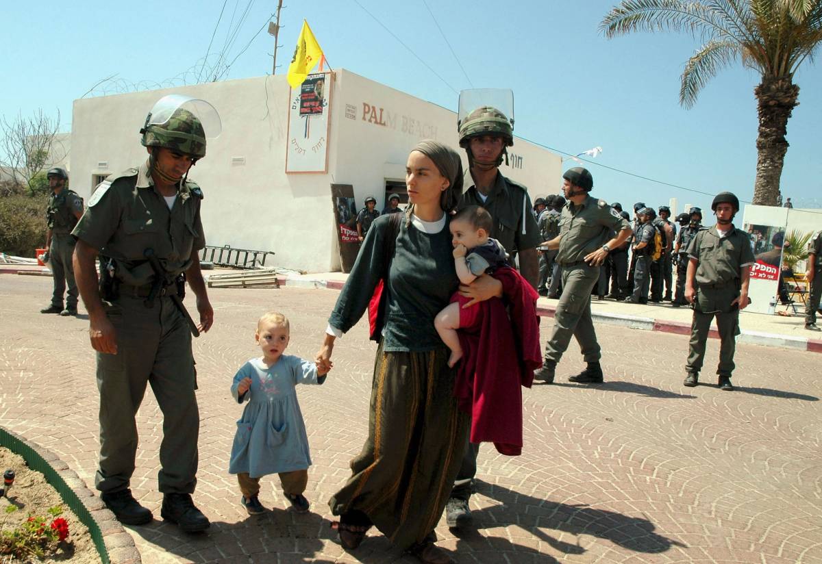 Israeli Border Police accompany a woman and her children during the evacuation of Jewish settlers from the Palm Beach Hotel in Gush Katif, 2005