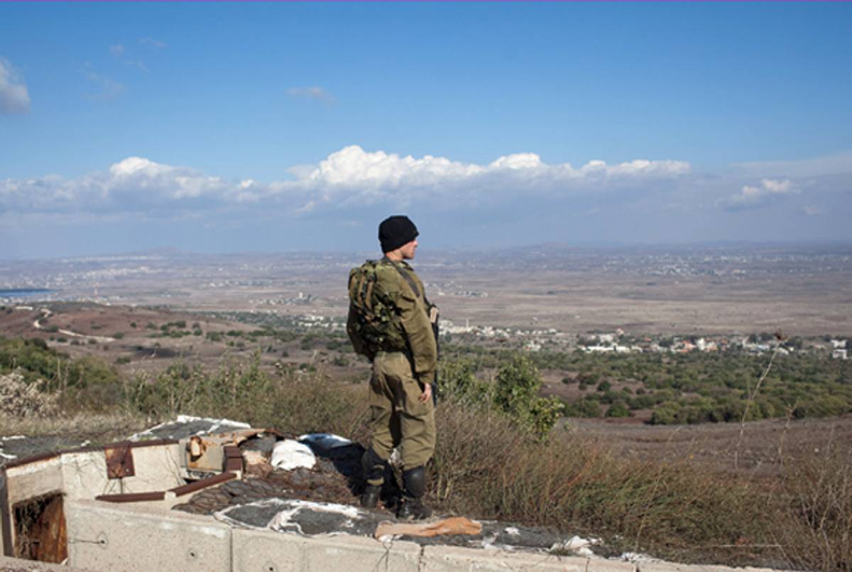 An Israeli soldier looks on as he stands on the border with Syria at the Israeli-annexed Golan Heights, overlooking the Syrian village of Breqa on November 13, 2012 in the Golan Heights.(Uriel Sinai/Getty Images)