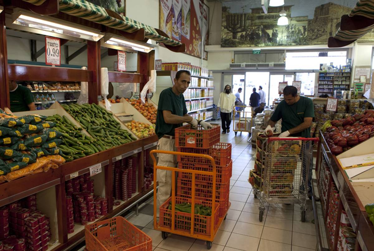 Palestinian workers put on display vegetables at a large Jewish-owned supermarket located in Gush Etzion Junction on July 4, 2010.(Menahem Kahana/AFP/Getty Images)