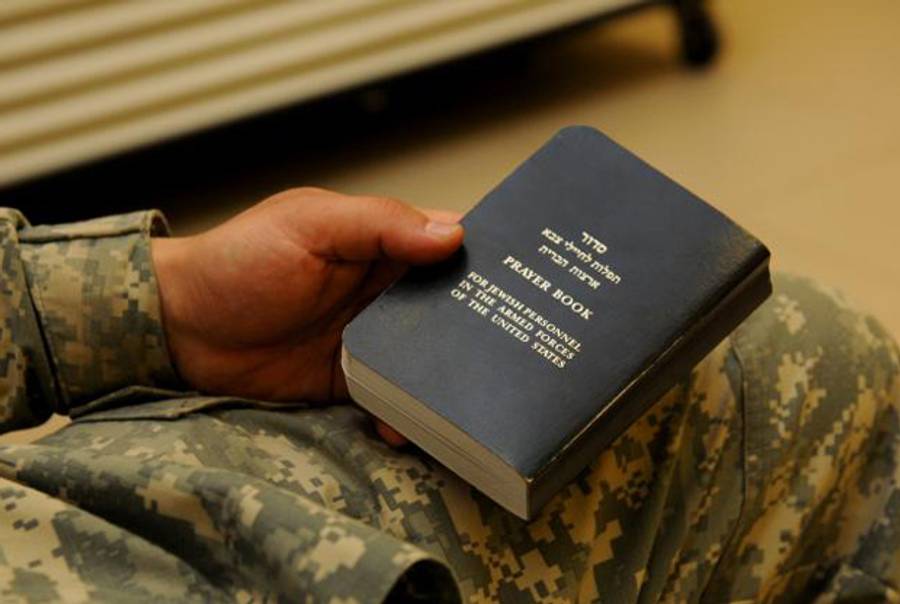 A Soldier holds a Jewish prayer book before a Task Force Marne Jewish Passover celebration and dinner, March 29, at the Freedom Rest, Contingency Operating Base Speicher, Iraq.(U.S. Army)