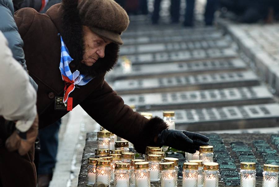 A survivor puts down a candle during a ceremony in the former Nazi concentration camp Auschwitz-Birkenau in Oswiecim, Poland, on International Holocaust Remembrance Day, January 27, 2014.(JANEK SKARZYNSKI/AFP/Getty Images)