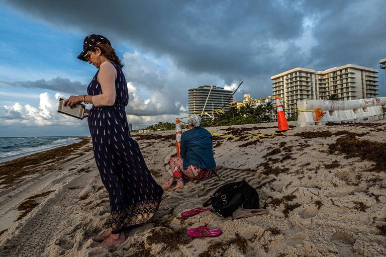 Neighbors pray at the seashore, near the Champlain Towers building, which had partially collapsed, on June 27, 2021, in the city of Surfside, Florida