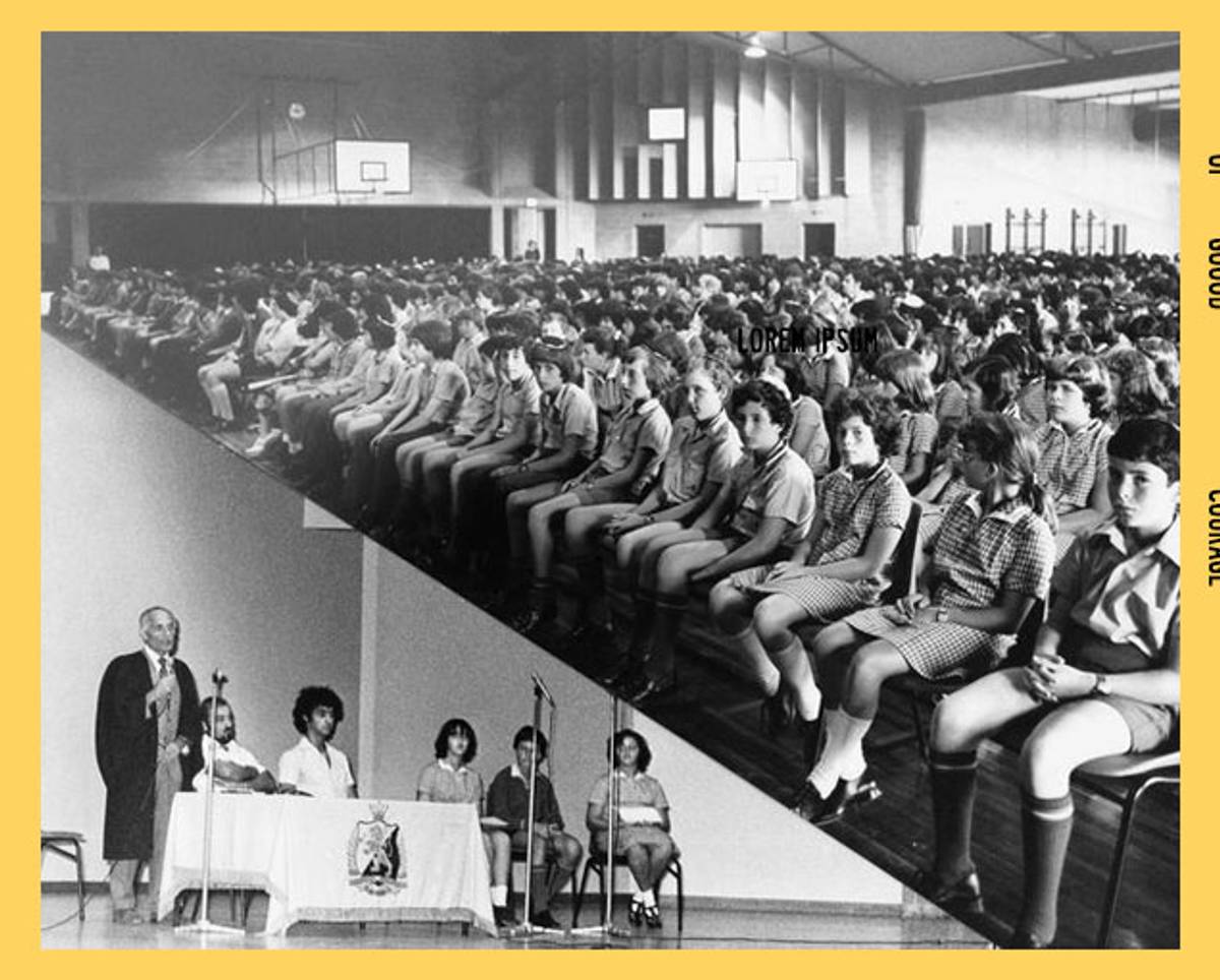 Mr. Ranoschy, standing, at bottom left, addresses students at assembly, 1977. The school's emblem can be seen on the table covering.