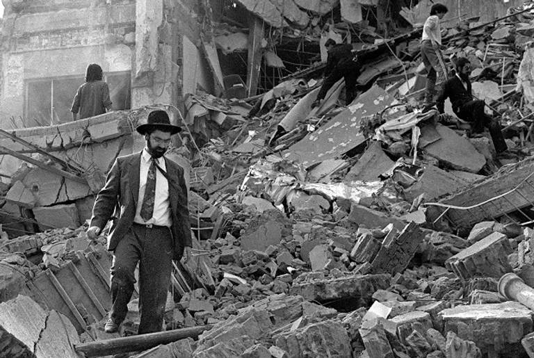 A man walks over the rubble left after a bomb exploded at the Argentinian Israeli Mutual Association (AMIA in Spanish) in Buenos Aires, 18 July 1994. (AFP/Getty Images)