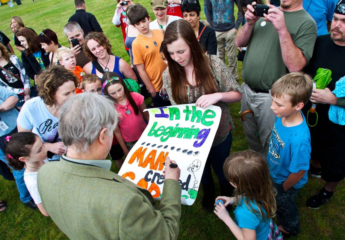 Richard Dawkins signs a poster reading ‘In the beginning, MAN created GOD’ for Andrea Garber, 15, at center, during the Rock Beyond Belief festival at Fort Bragg army base in North Carolina on March 31, 2012