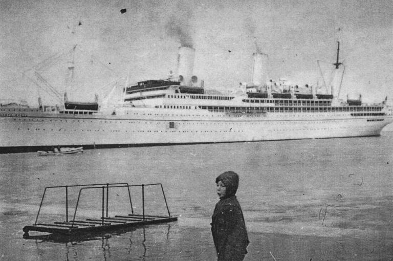 Four-year-old Bill Hant in front of SS Conte Rosso, the sister ship of SS Conte Verde, at the port of Trieste