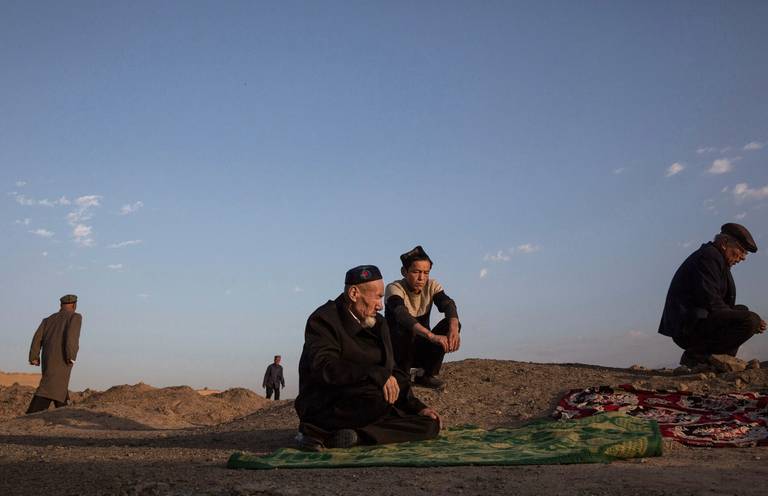 Uyghur men gather to pray at a grave in Turpan County, Xinjiang, China