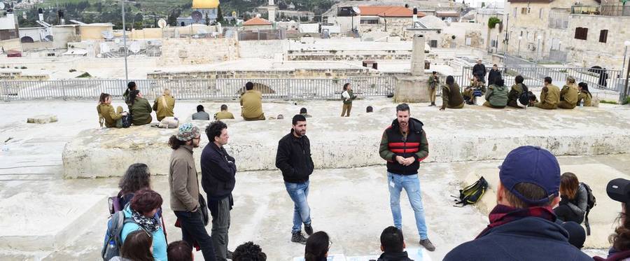 Israeli tour guide Shai Goren talks about the borders and population of Jerusalem, while Palestinian tour guide Noor Awad, second from right, listens, during a recent dual-narrative tour of the ancient and contested city.