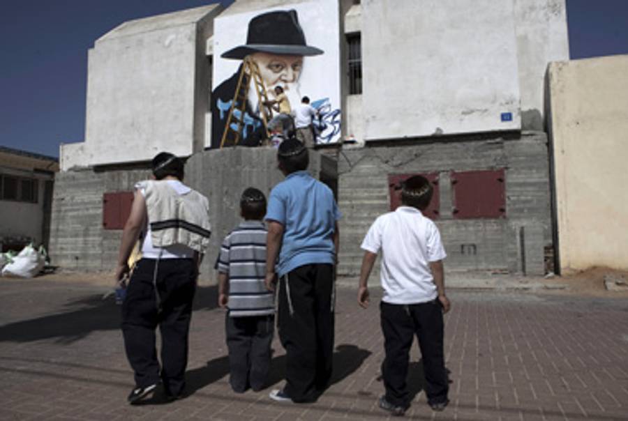 Children watch as Spanish graffiti artists work on a large spraypainted portrait of Menachem Mendel Schneerson on the outside of a bomb shelter in the Israeli town of Sderot, April 27, 2010.(Menahem Kahana/AFP/Getty Images)