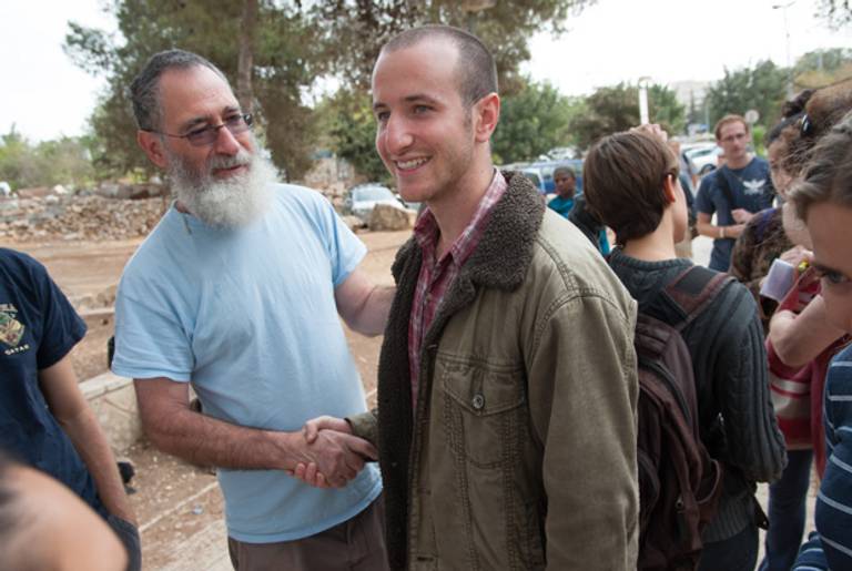 Yoav Hass, a member of Yesh Gvul, offers a supportive handshake to Moriel Rothman as he prepares to report to his draft location at Ammunition Hill, and refuse to participate in the Israeli military, Oct. 24, 2012.(Ryan Rodrick Beiler/ActiveStills)