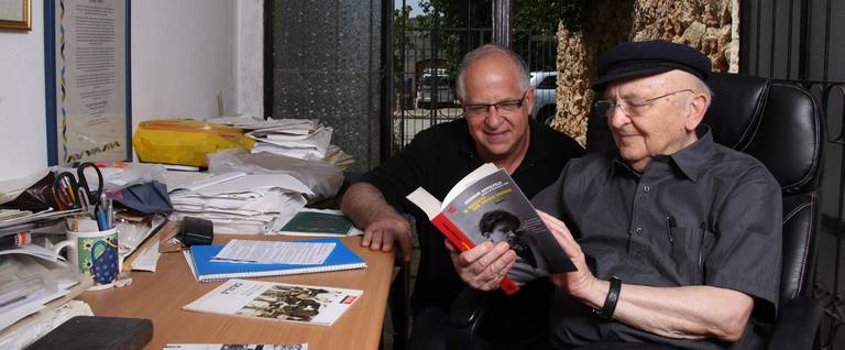 Aharon Appelfeld holds one of his books as he sits with his editor, Professor Yigal Schwartz, Mevaseret Zion, 2012.