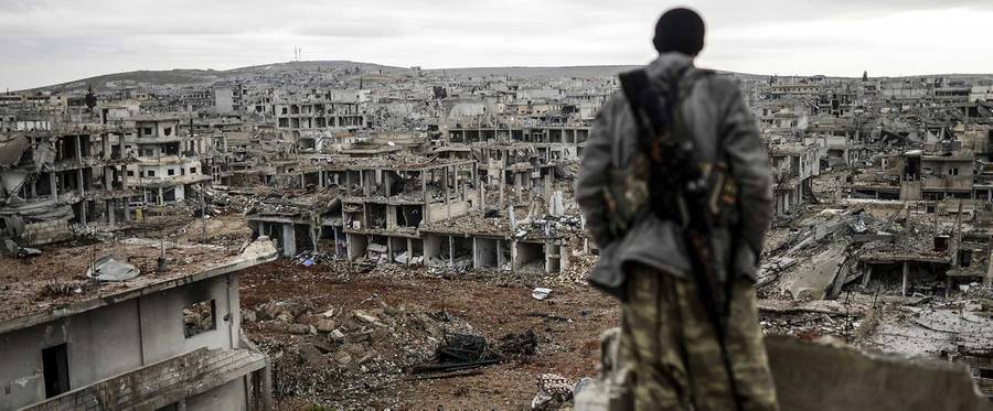 Musa, a 25-year-old Kurdish marksman, stands atop a building as he looks at the destroyed Syrian town of Kobane, also known as Ain al-Arab, on Jan. 30, 2015. 