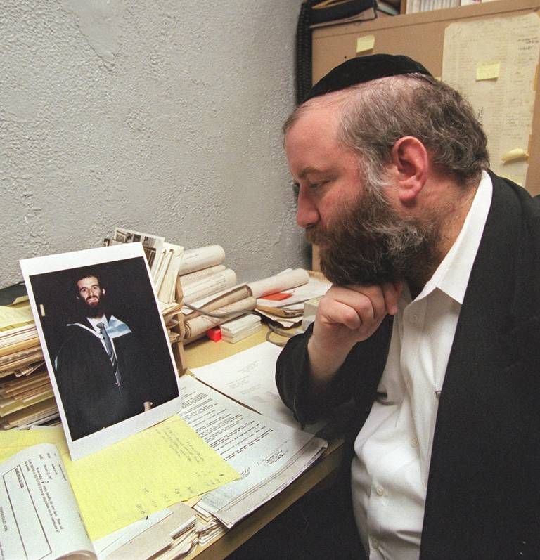 Norman Rosenbaum looks at a photograph of his slain brother, Yankel, at Norman's improvised office at the back of a friend's hardware store in New York, in 1997