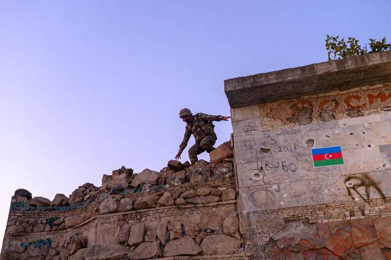 An Azeri soldier passes over a wall in the city of Jabrayil, where Azeri forces regained control during fighting with Armenia over the breakaway region of Nagorno-Karabakh, on Oct. 16, 2020