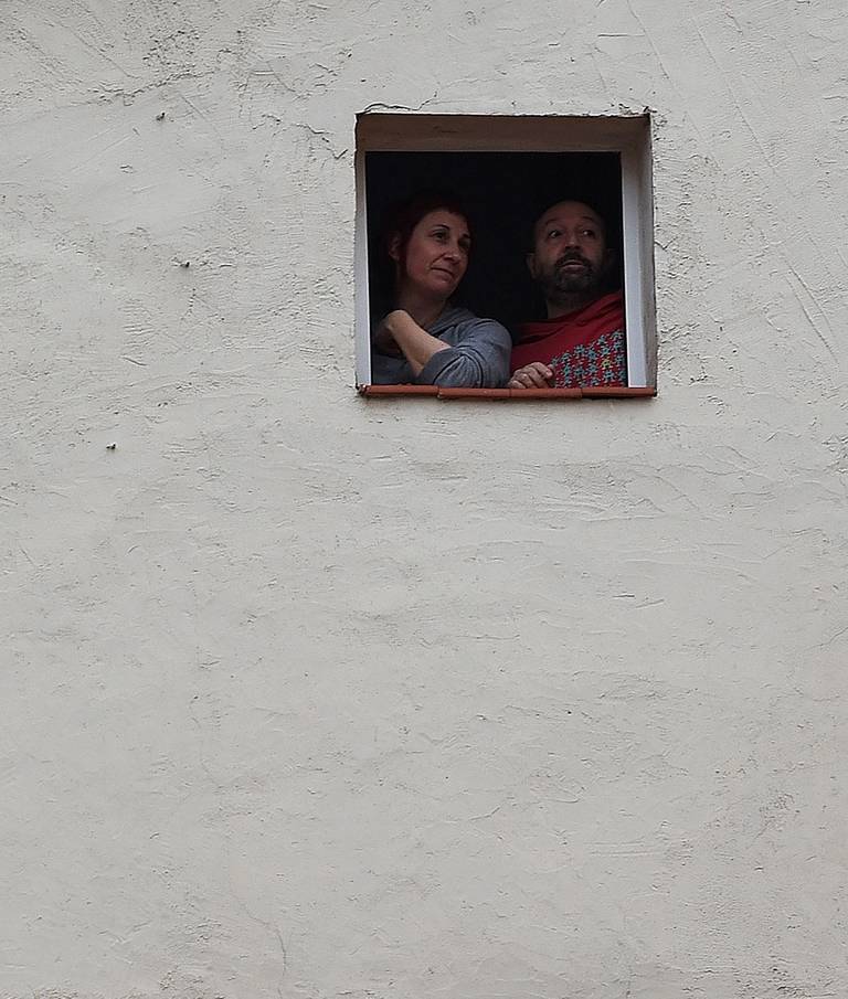 A couple chat with neighbors from their window in Madrid on April 4, 2020