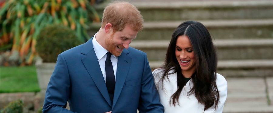 Britain's Prince Harry stands with his fiancée US actress Meghan Markle as she shows off her engagement ring whilst they pose for a photograph in the Sunken Garden at Kensington Palace in west London on November 27, 2017, following the announcement of their engagement. Britain's Prince Harry will marry his US actress girlfriend Meghan Markle early next year after the couple became engaged earlier this month, Clarence House announced on Monday.