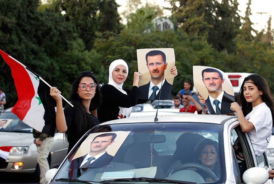 Syrian girls wave portraits of Syria's President Bashar al-Assad as pro-regime supporters parade their cars in Damascus to celebrate Assad's 48th birthday on Sept. 11, 2013.(Anwar Amro/AFP/Getty Images)