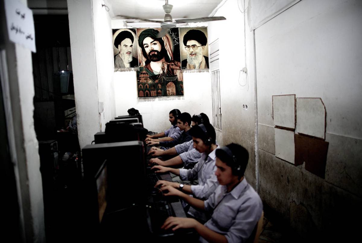 Iranian youth play at an arcade that is decorated with portraits of Iran's late founder of Islamic Republic, Ayatollah Ruhollah Khomeini (L), supreme leader Ayatollah Ali Khamenei (R), and an Islamic religious portrait, in the city of Qom, on June 9, 2013.(Behrouz Mehri/AFP/Getty Images)
