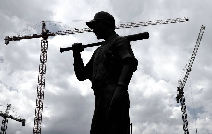 A silhouetted bronze statue of a baseball player in front of Denver’s Coors Field