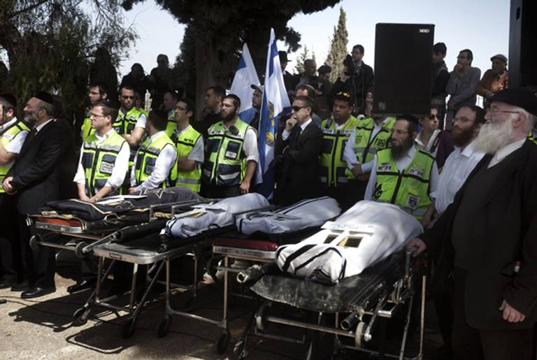 Mourners and Israeli Zaka Volunteers stand around the bodies of teacher Jonathan Sandler (R), and his children Gabriel 4, Arieh 5, and Miriam Monsonego 7 (L) victims of the Toulouse school shooting, during their funeral in Jerusalem March 21, 2012.(Menahem Kahana/AFP/Getty Images)
