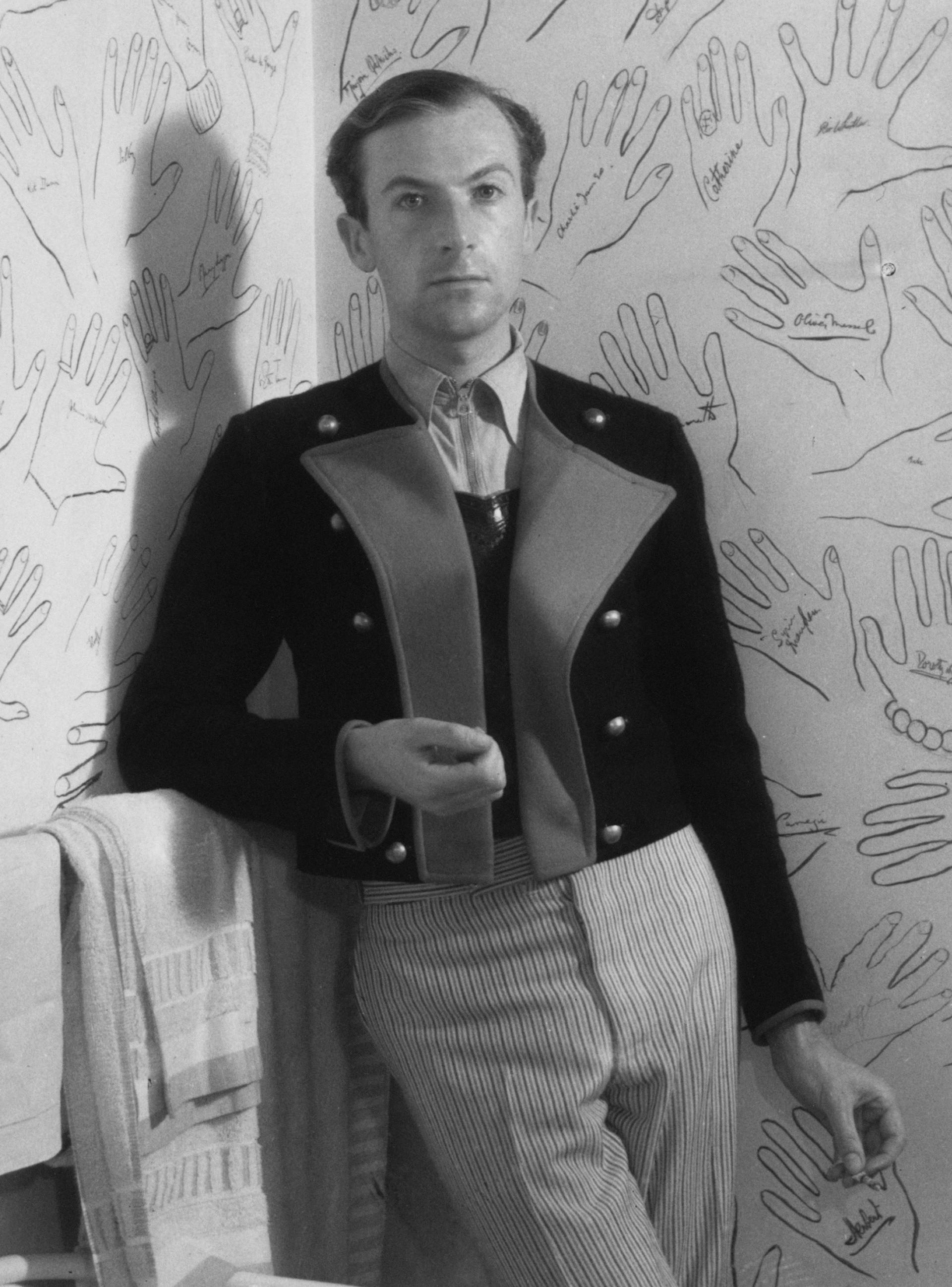 Cecil Beaton in the bathroom of his home in Wiltshire, showing the walls decorated with autographed hands of guests, 1934