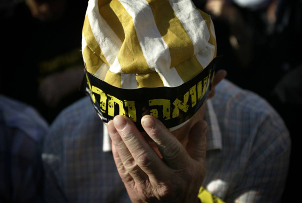 During a protest next to the prime minister's office in Jerusalem on August 5, 2007, an Israeli survivor of the Holocaust adjusts his cap, with a sticker that reads in Hebrew: "Holocaust and Shame." (Emilio Morenatti/AP)