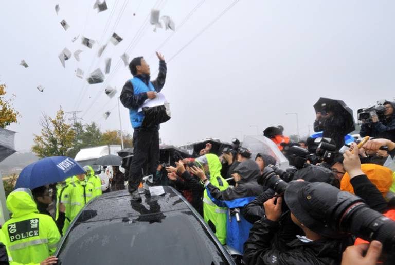 Park Sang Hak, an activist and former defector from North Korea, scatters anti-Pyongyang leaflets as police block his planned rally near the tense border on a roadway in Paju, north of Seoul, on Oct. 22, 2012. (Jung Yeon-Je/AFP/Getty Images)