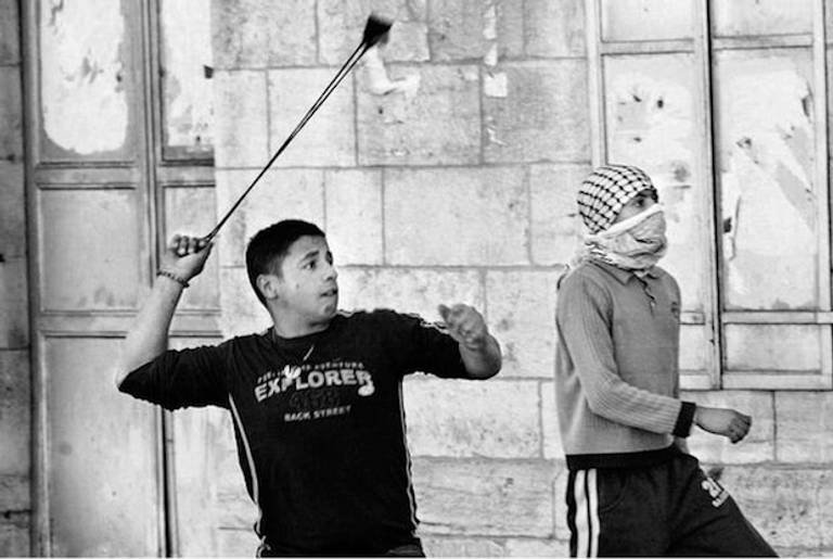 A Palestinian hurls a stone towards an Israeli armywatch-tower during clashes in Bethlehem in March 2007(HinduTimes)