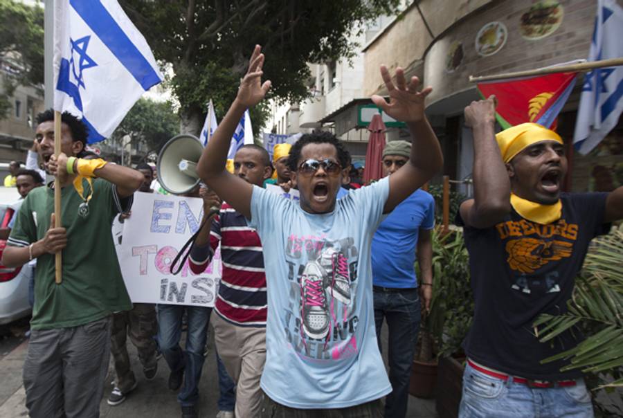 Eritreans, holding banners and the Israeli (L) and Eritrean flags (R), shouts slogans as they walk from Levinsky Park to the US Embassy in the southern Mediterranean coastal city of Tel Aviv on June 29, 2012, to demonstrate against institutionalized racism and new deportation regulations introduced in Israel.(JACK GUEZ/AFP/GettyImages)
